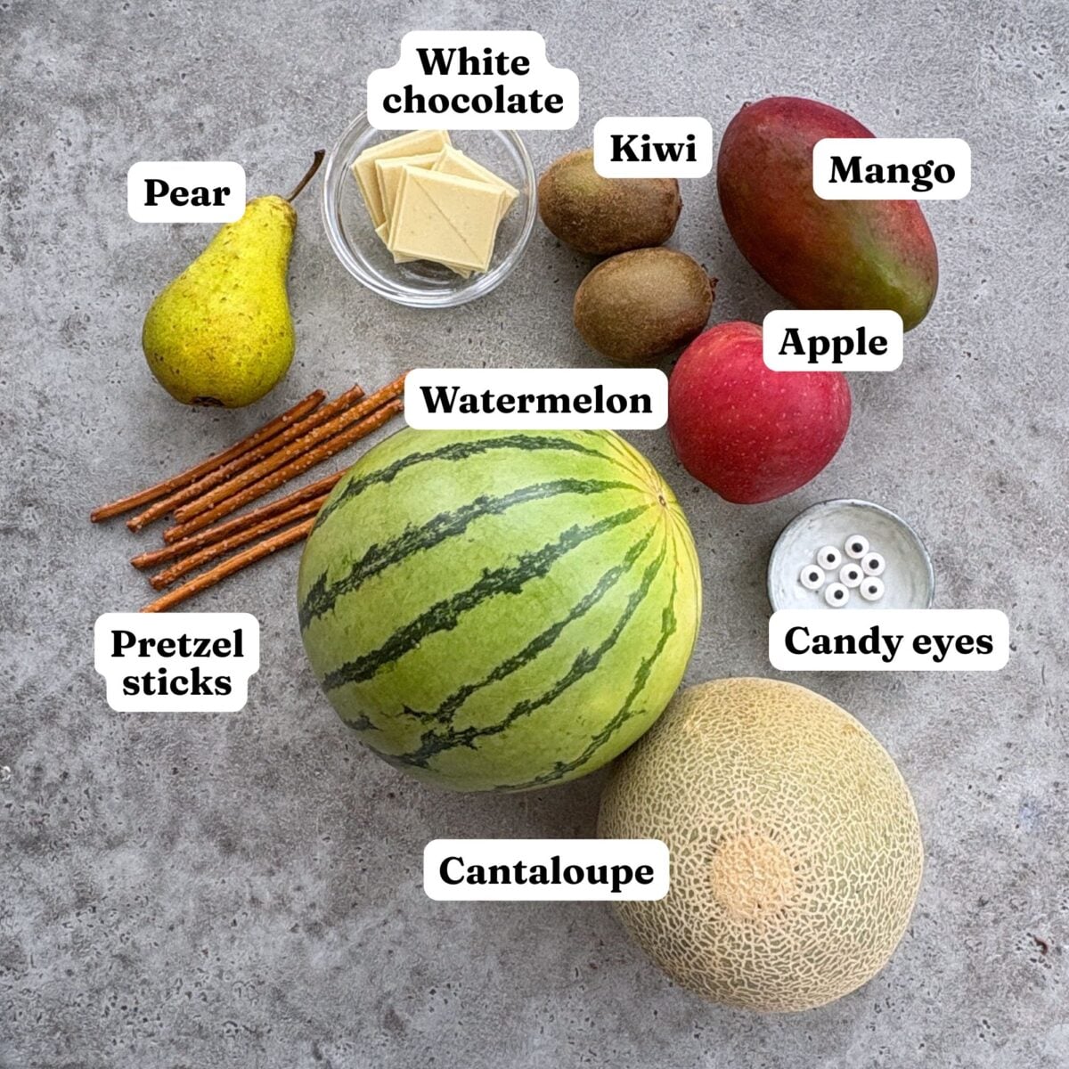 Pear, white chocolate, kiwi, mango, apple, pretzel sticks, watermelon, candy eyes, and cantaloupe.