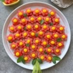 A round plate displays a delightful fruit bouquet of flower-shaped watermelon slices topped with yellow mango balls.