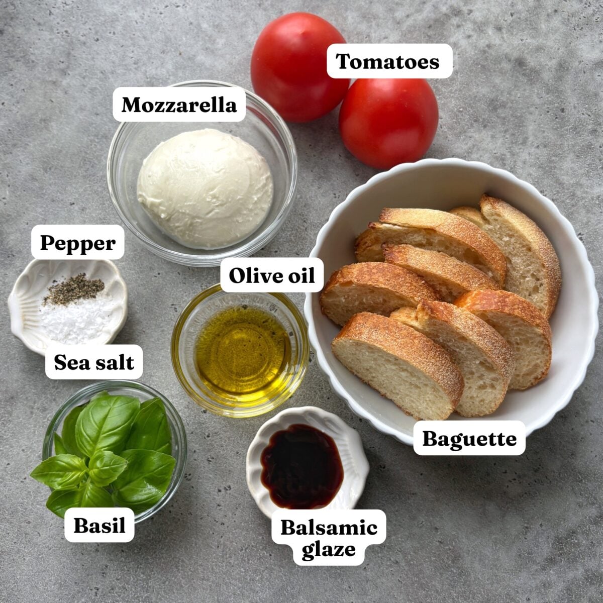 Tomatoes, mozzarella, pepper, sea salt, basil, olive oil, balsamic glaze, and a bowl of sliced baguette.