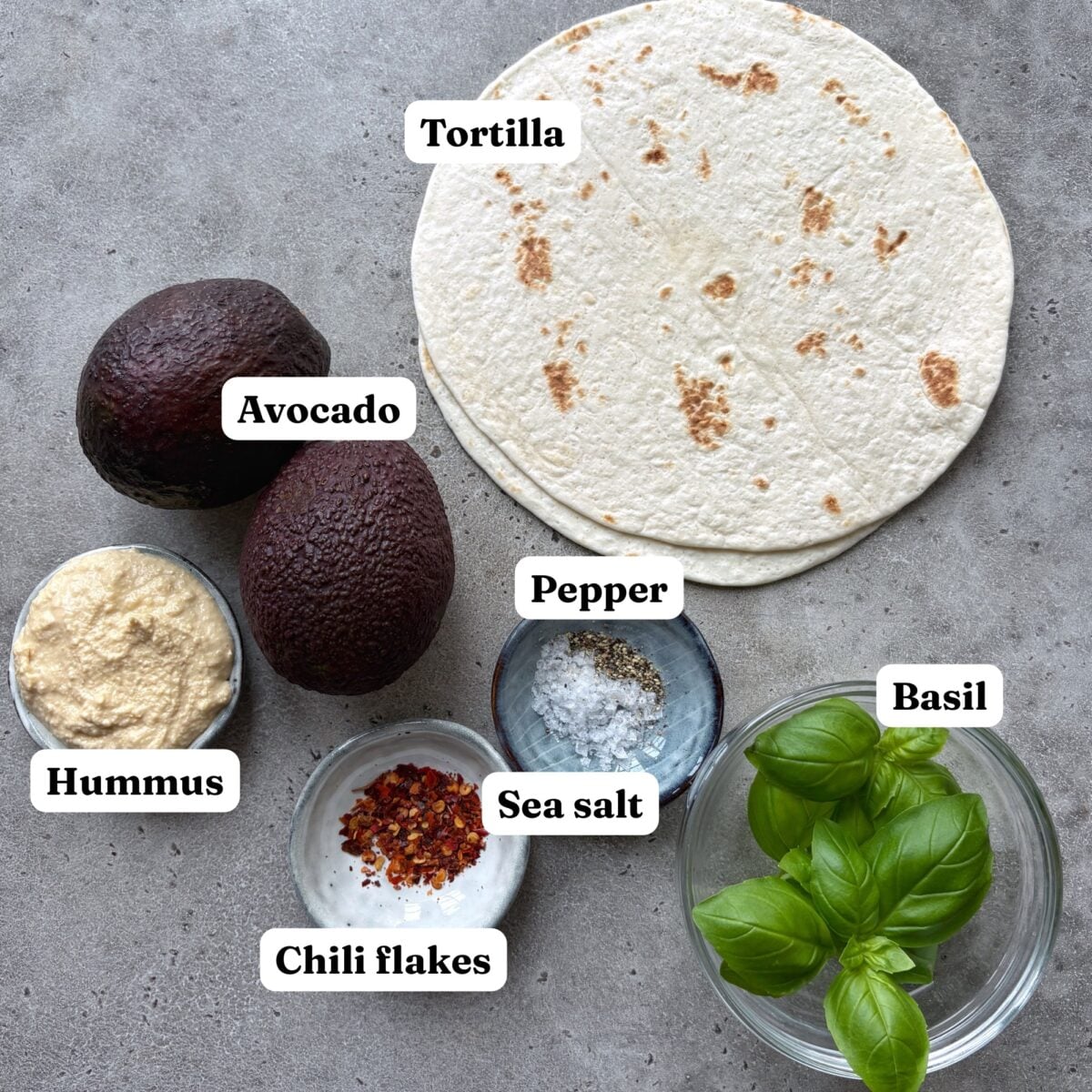 Tortillas, avocados, hummus, pepper, sea salt, chili flakes, and fresh basil, all labeled.