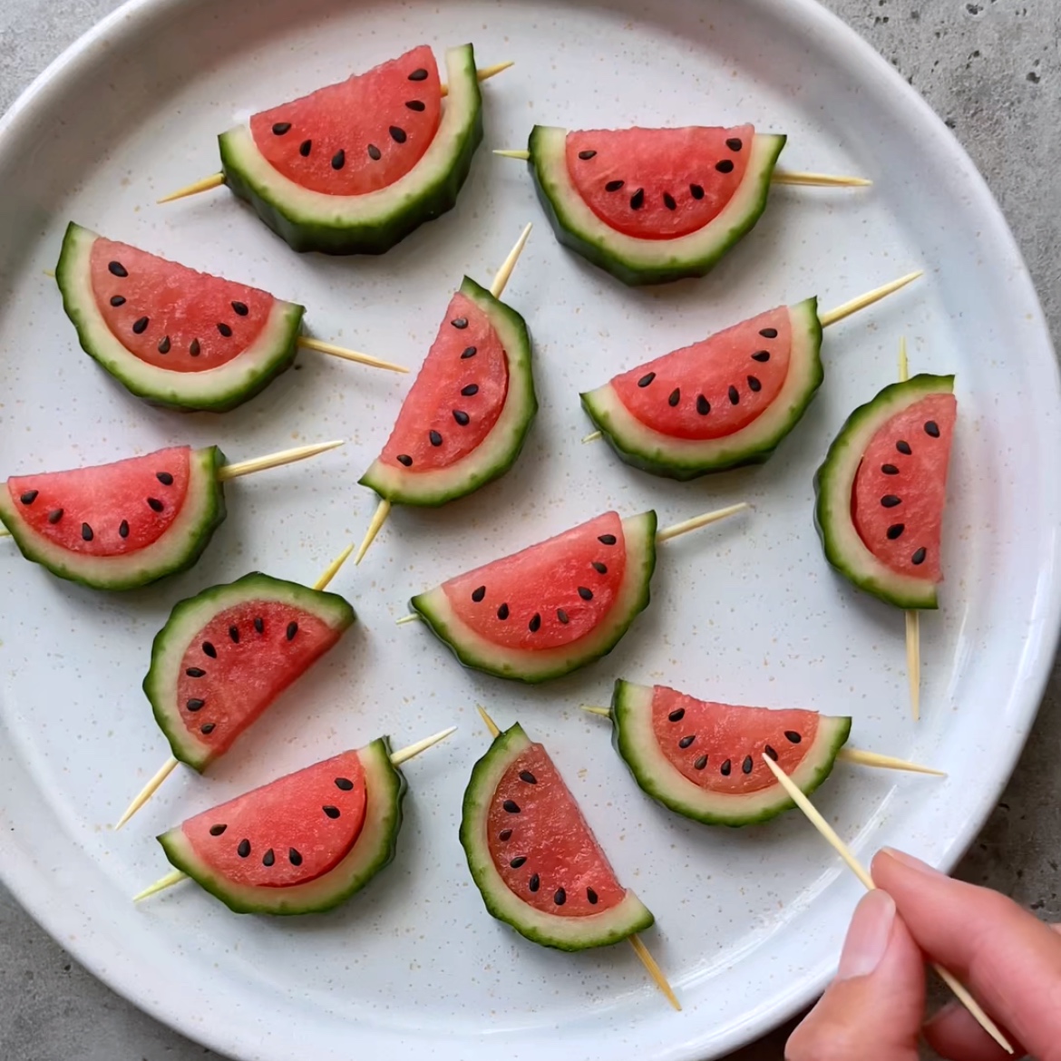 A white plate with Mini Watermelon Snacks on toothpicks arranged in a circle.