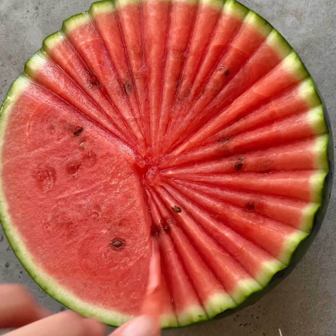 A hand removes a shard of watermelon. 