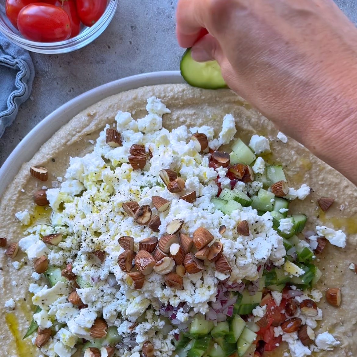 A person putting a cucumber on a tortilla, perfect for creating a fresh twist on a layered hummus dip.