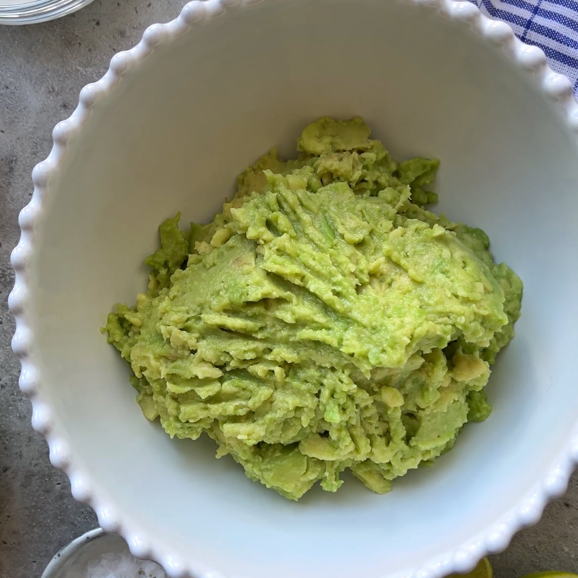 A white bowl filled with creamy Guacamole Dip sits on a countertop.