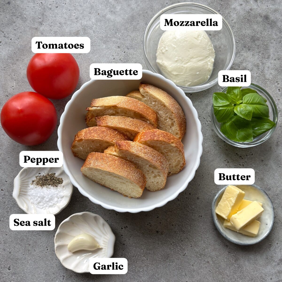 Sliced baguette, tomatoes, mozzarella, basil, butter, garlic, sea salt, and pepper.