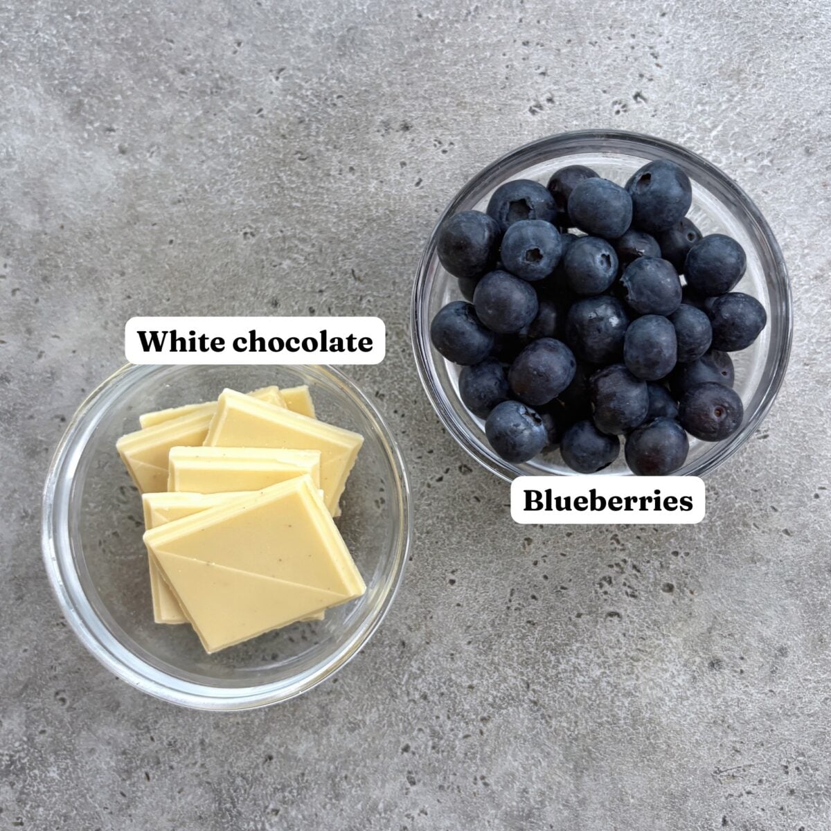 White chocolate and fresh blueberries in separate bowls.