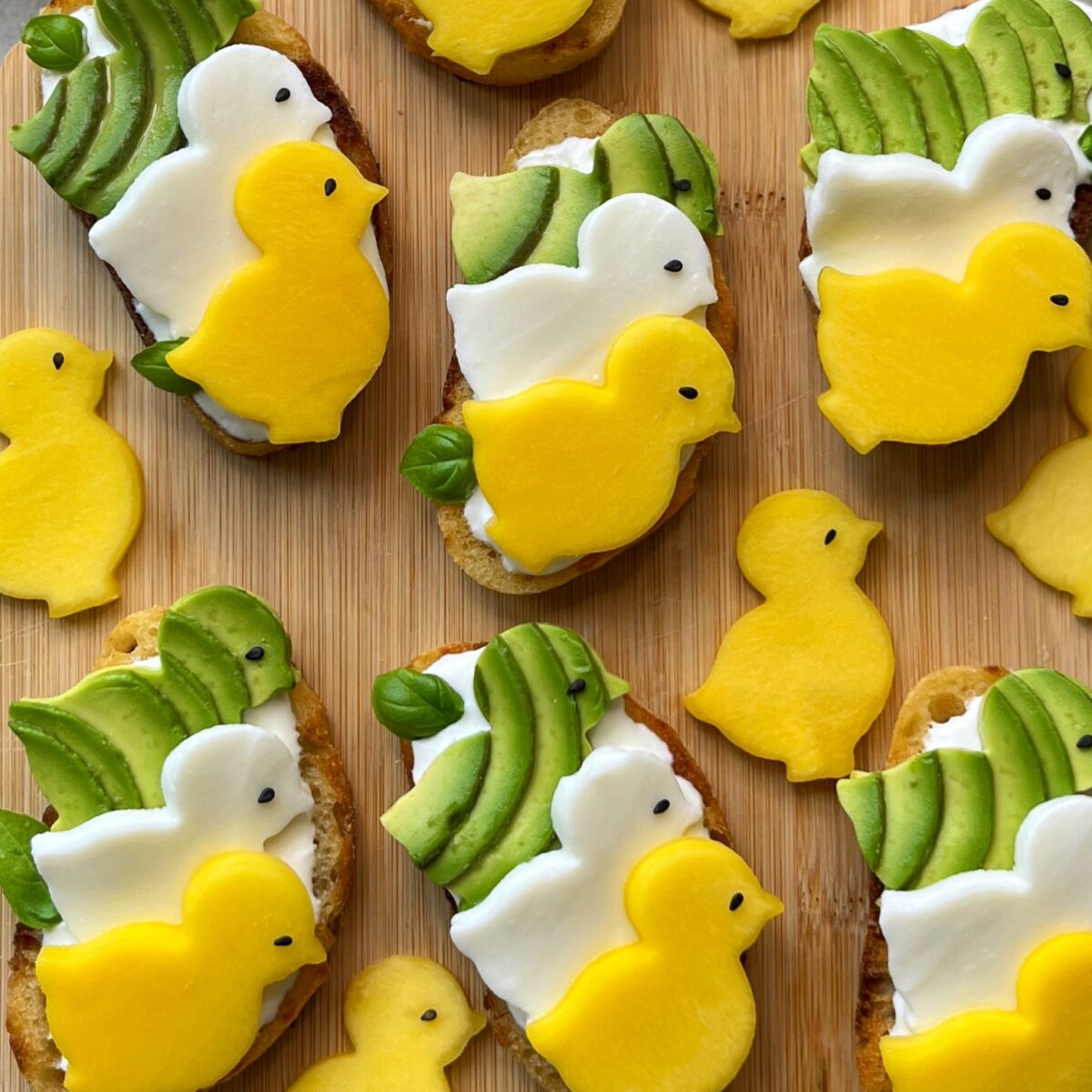 Sliced bread topped with avocado, cream cheese, and mango chicks.