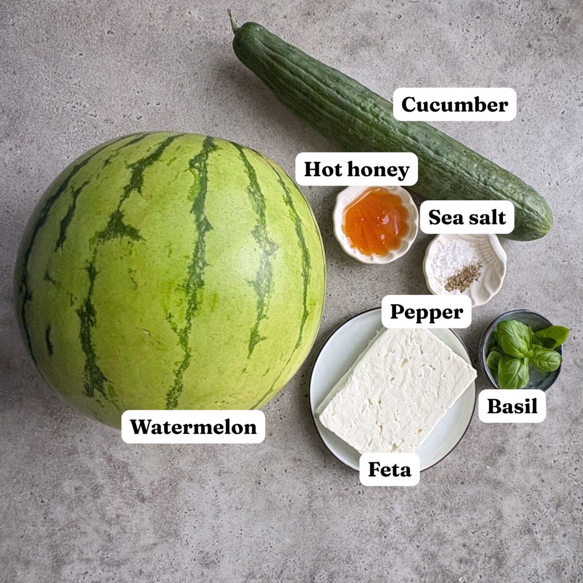 A watermelon, a cucumber, feta cheese, hot honey, sea salt, pepper, and fresh basil.