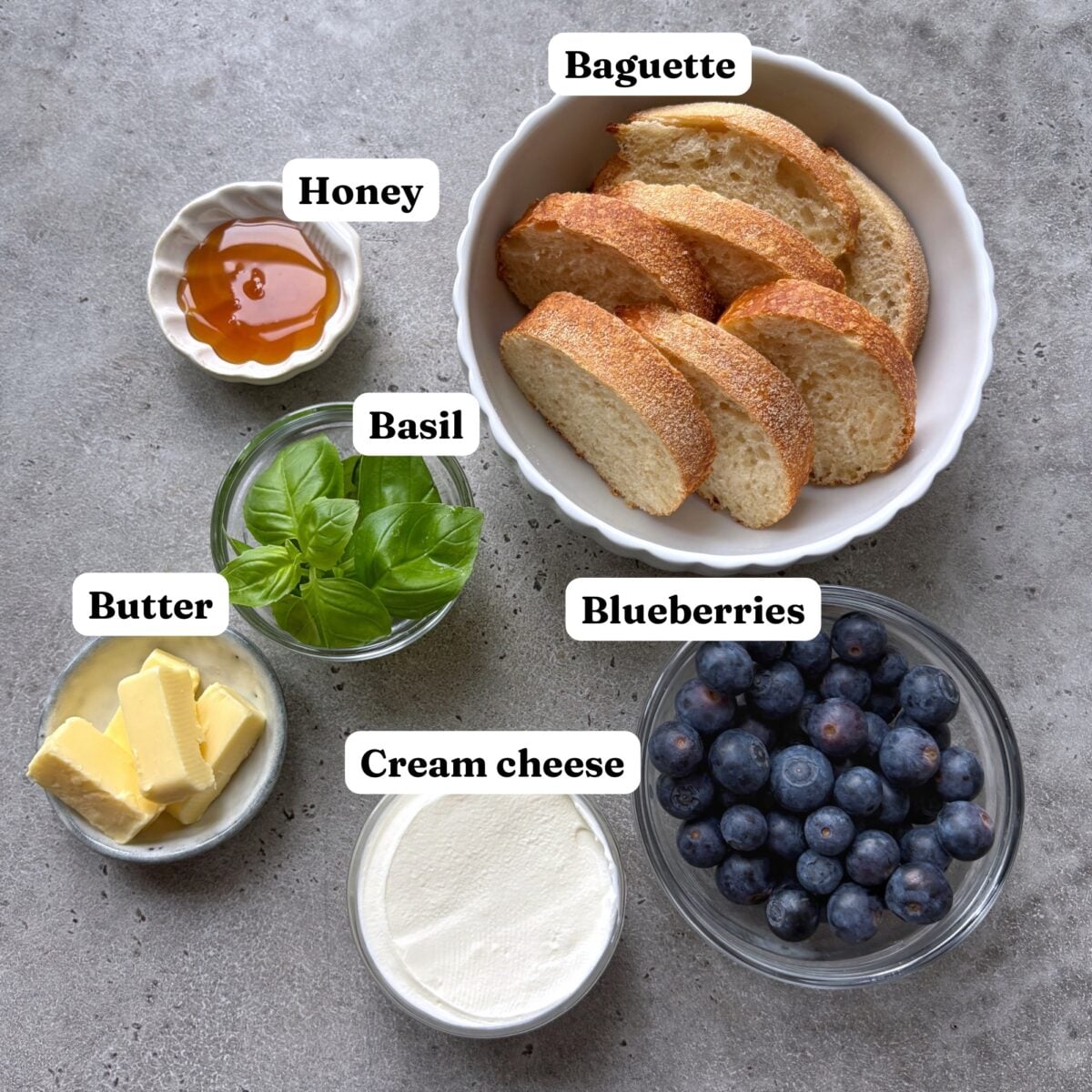 Sliced baguette, cream cheese, honey, fresh basil, butter, and blueberries.