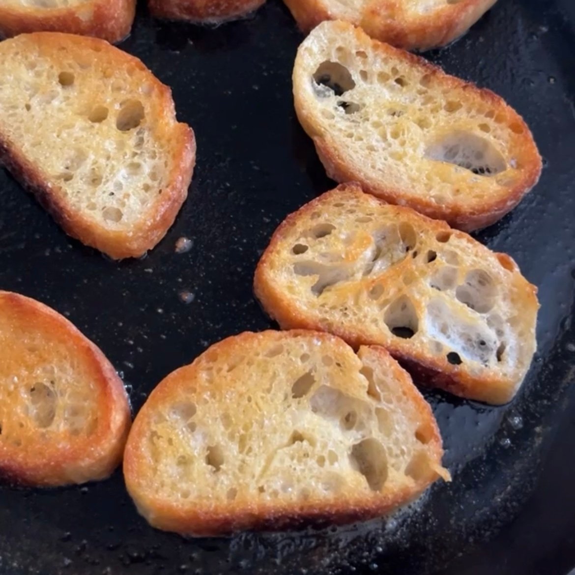 Slices of bread being toasted in a pan.