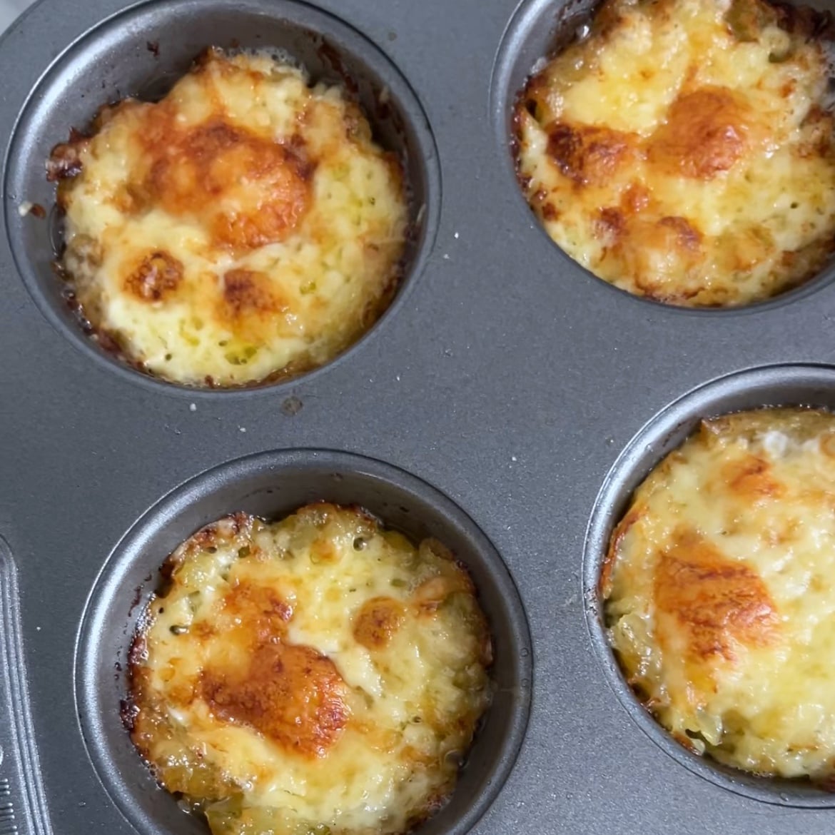 Four golden-baked cheesy smashed potatoes right out of the oven.