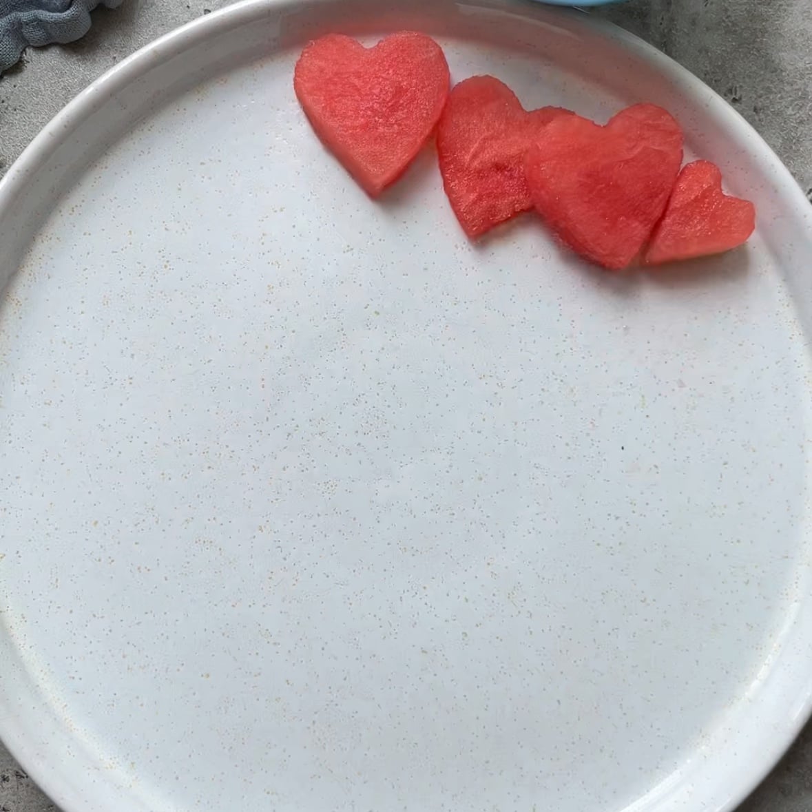 Watermelon hearts are placed in a straight line at the top of a platter.