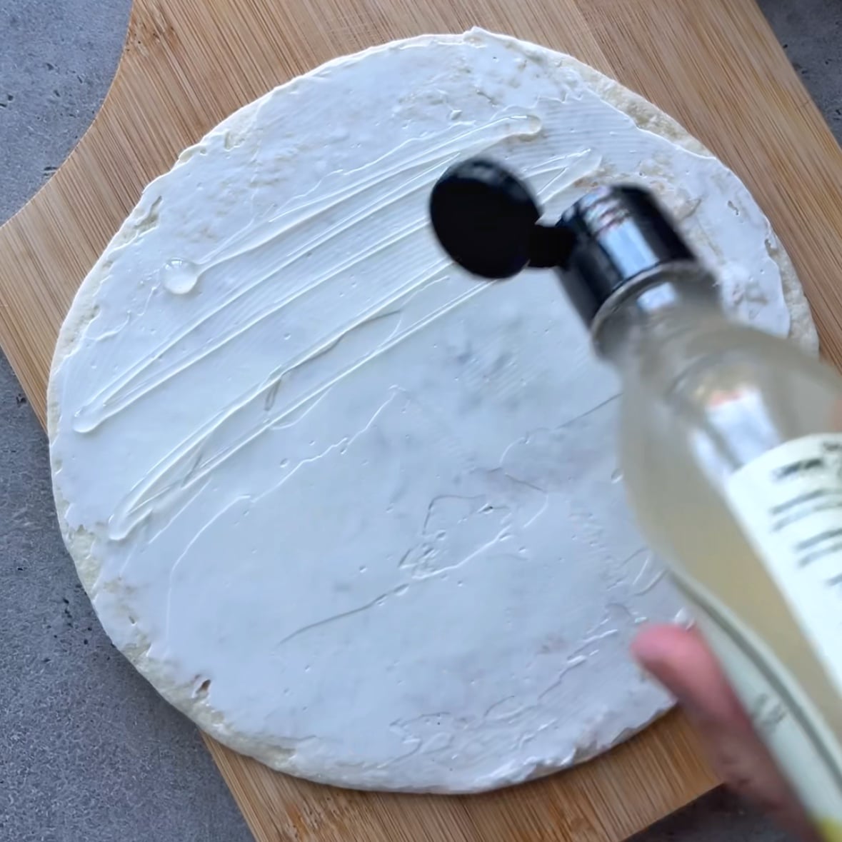 A tortilla is topped with cream cheese and white balsamic glaze.