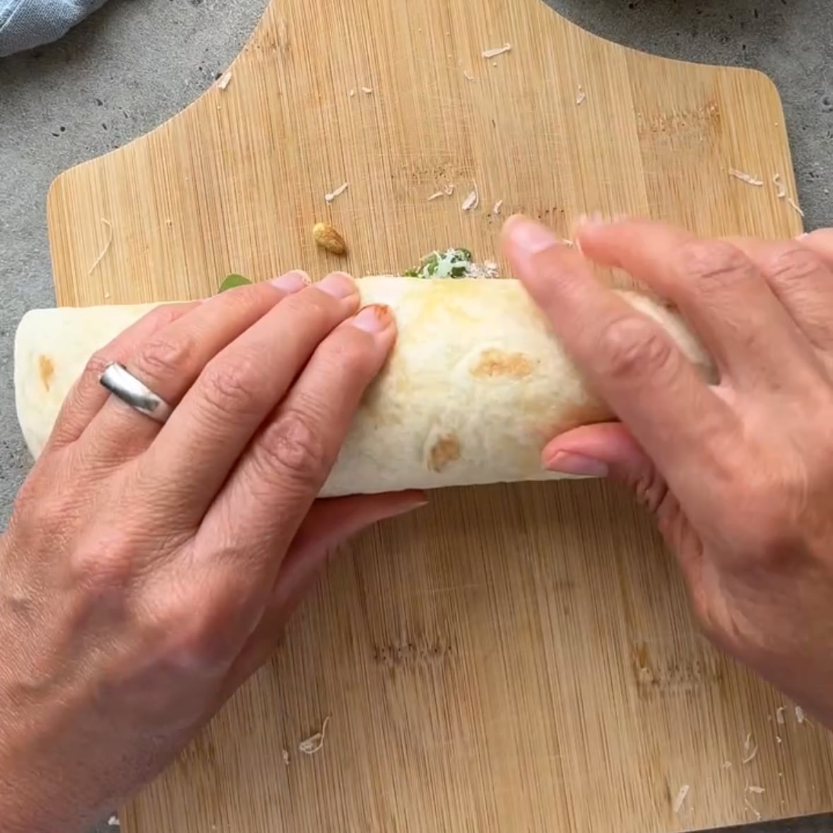 Two hands rolls up a bresaola carpaccio wrap.
