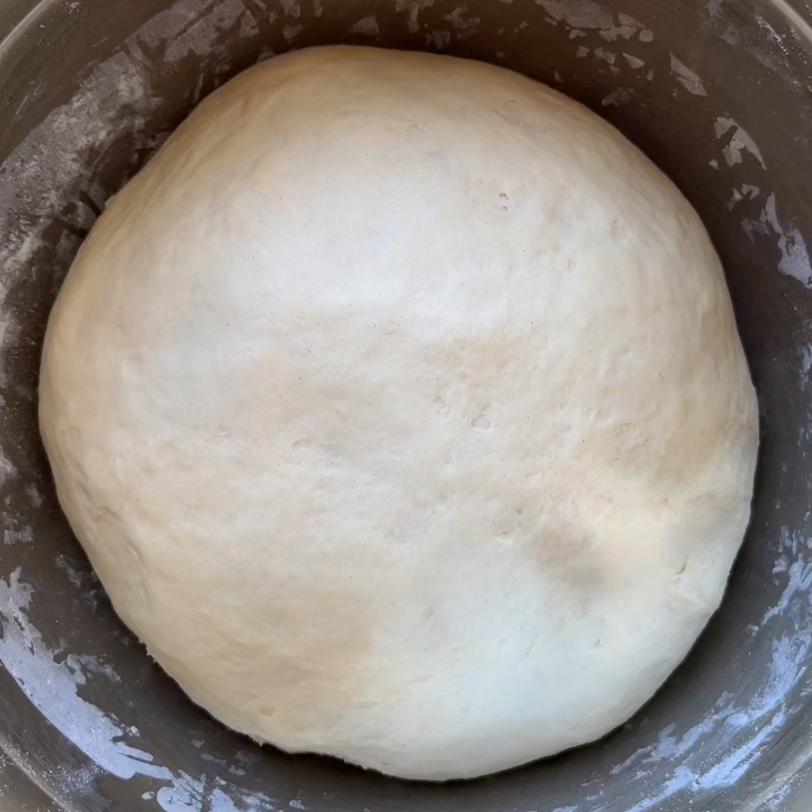 A ball of risen Halloween Bread dough sits in a bowl.