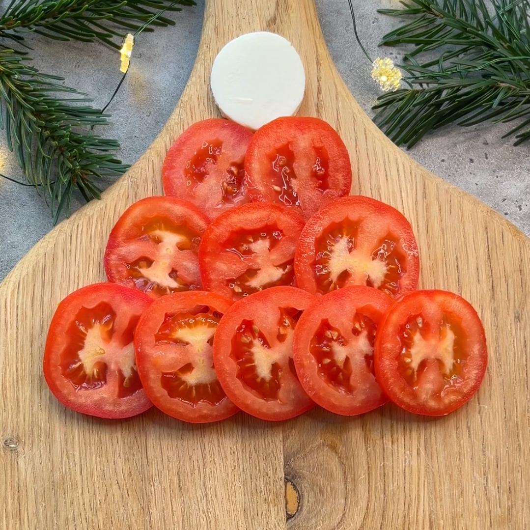 Santa's hat arranged on chopping board using mozzarella and tomato slices.