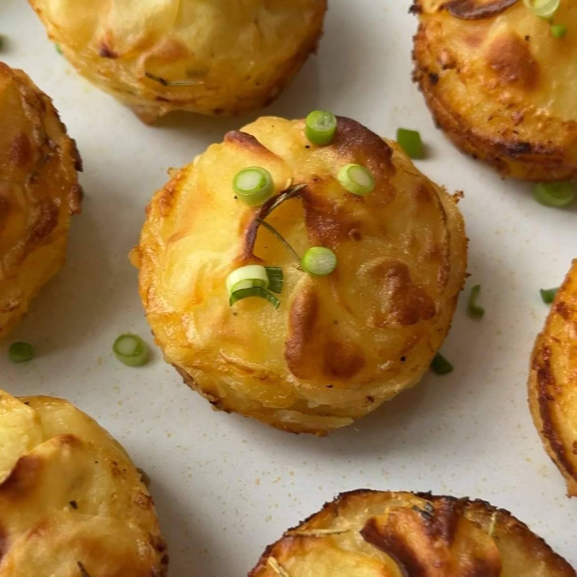 Golden brown Potato Stacks garnished with chopped green onions, arranged beautifully on a white plate.