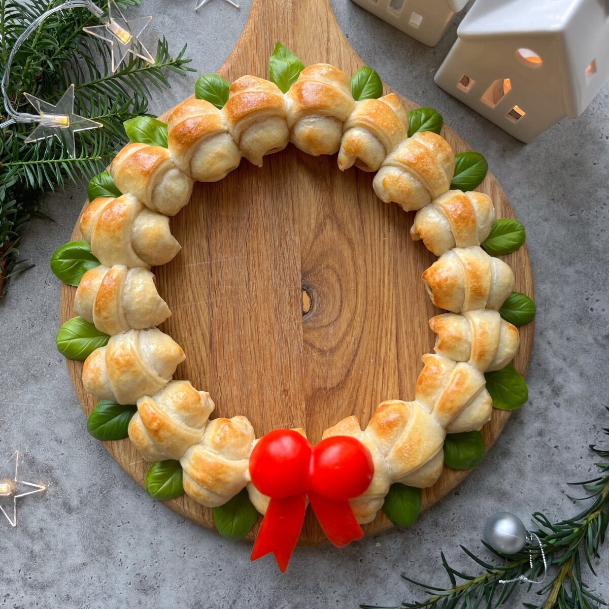 A festive Sausage Roll Wreath features a ring of baked rolls with basil leaves and a red pepper bow.