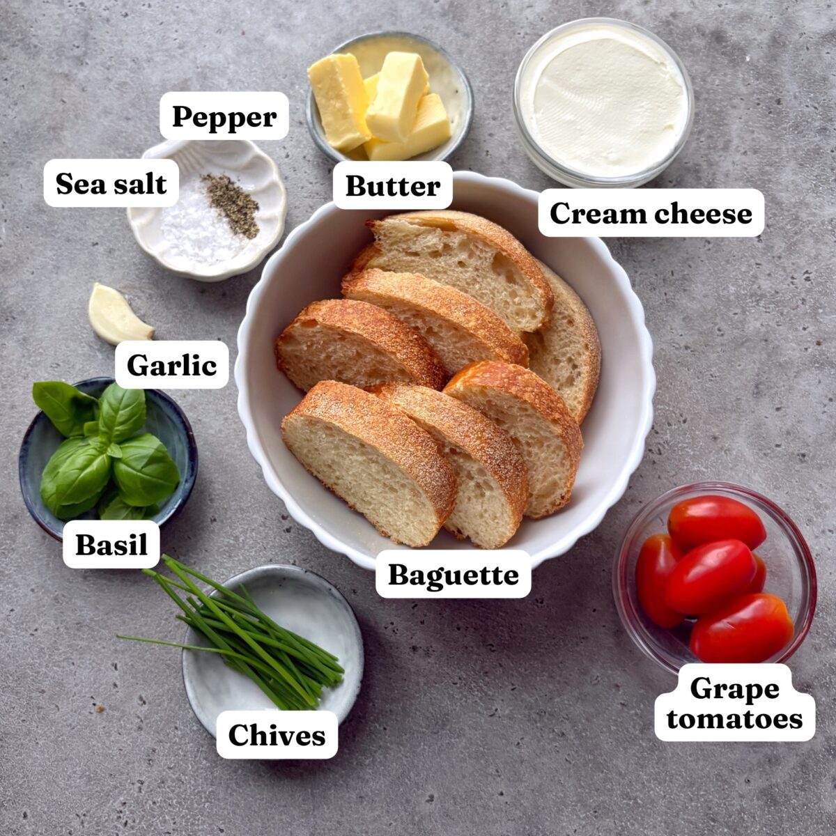 Butter, cream cheese, pepper, sea salt, garlic, basil, chives, baguette slices, and grape tomatoes.
