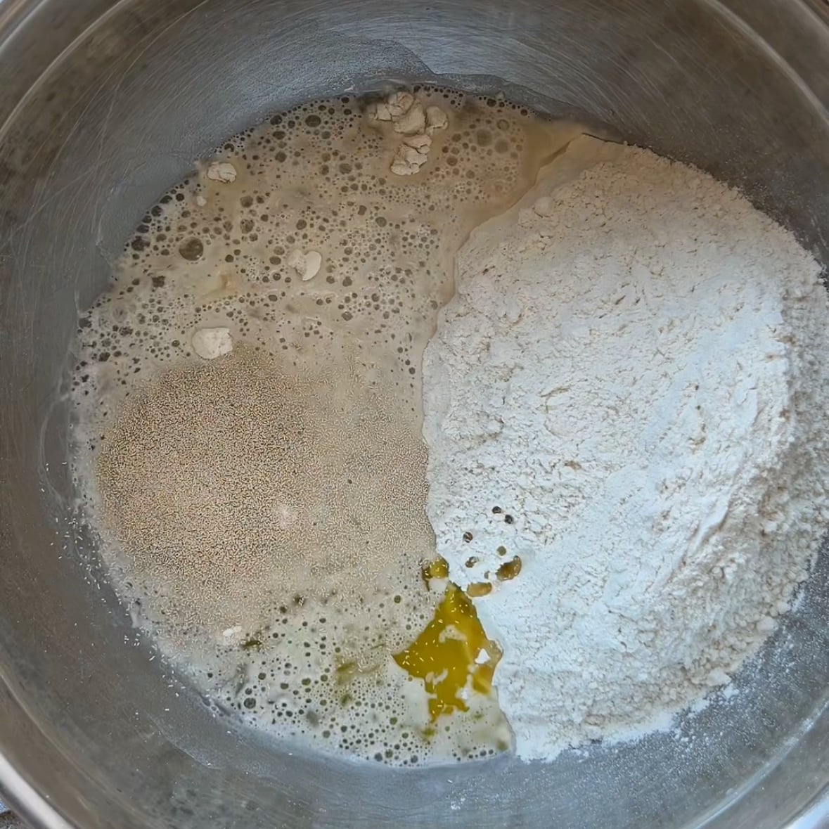 A large bowl containing flour, water, olive oil, yeast, and sea salt.