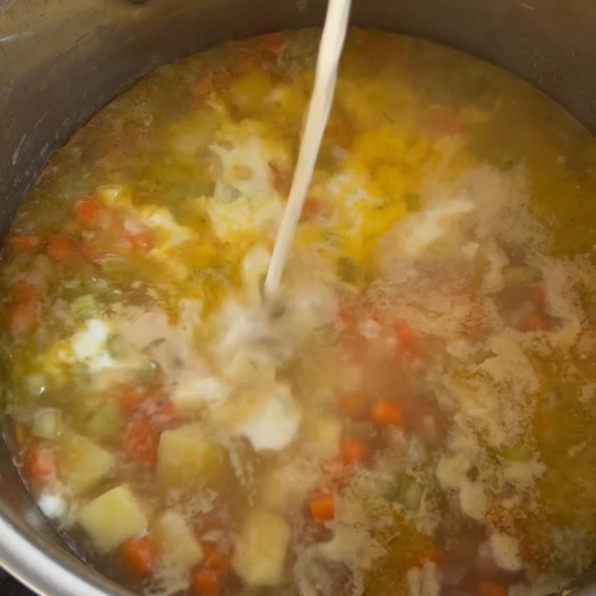 Cream is being poured into a pot of hearty Chicken Potato Soup.