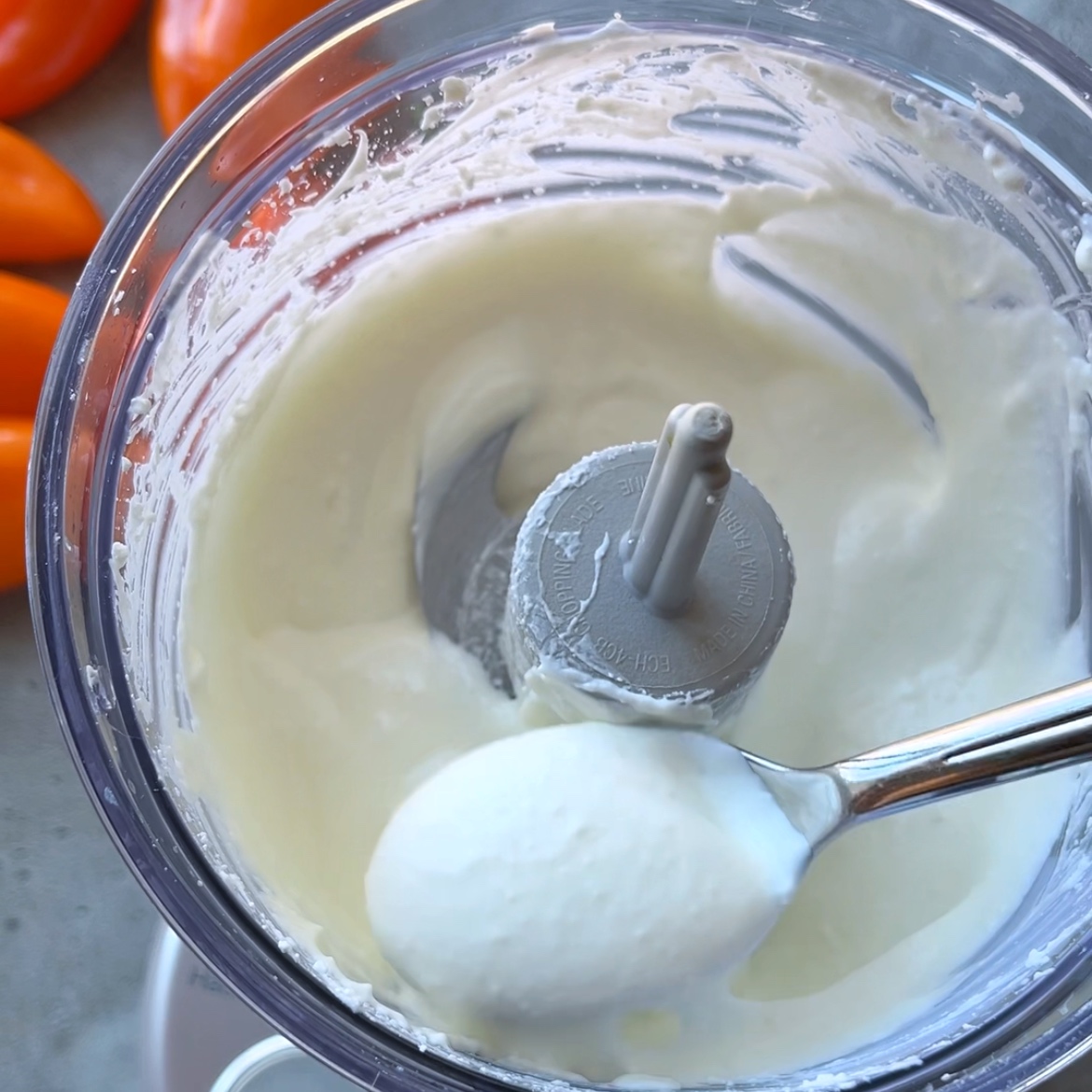A close-up of a food processor containing creamy whipped feta.