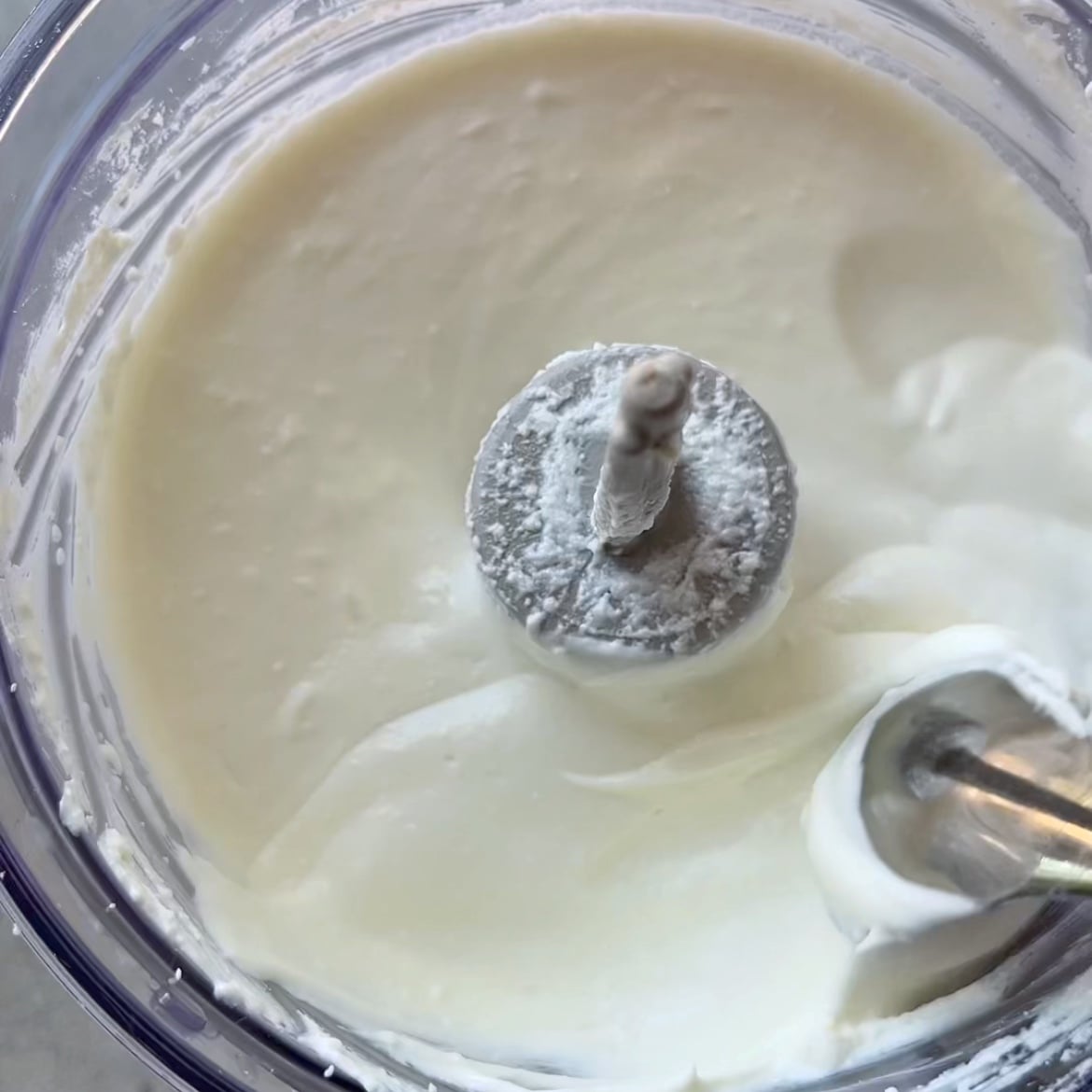 Close-up of a food processor mixing thick white Feta Cheese Dip.