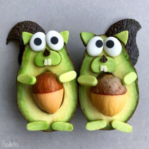 Two avocado halves decorated to look like squirrels, with dark peels as tails, nuts as bellies, and creative features for eyes, noses, teeth, arms, and feet from various foods—perfect for fun bites or inspiring healthy food recipes.