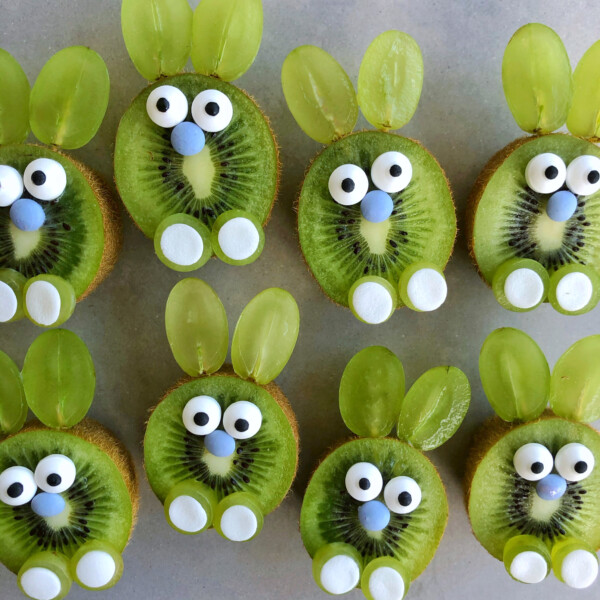 Kiwi slices decorated to look like bunnies using green grape halves for ears, candy eyes, blue candies for noses, and white candies for feet make adorable, healthy bites perfect for fun food recipes or creative dishes.