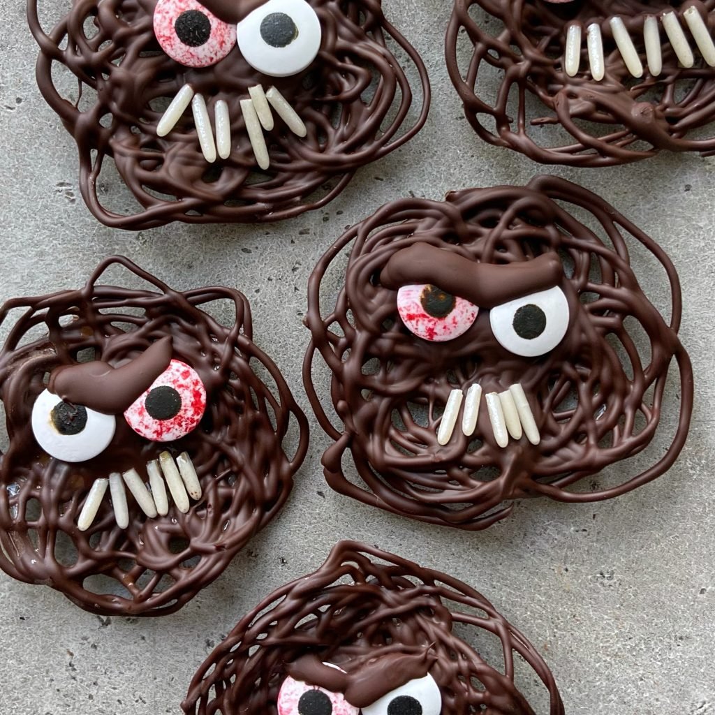 A group of swirled dark chocolate monsters with sprinkle teeth and candy eyes.