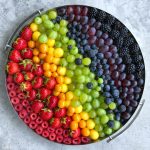 A round tray displays an array of fresh fruits arranged in rainbow-like rows—these colorful bites make for both a beautiful presentation and a health-conscious addition to your favorite food recipes.