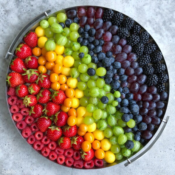A round tray displays an array of fresh fruits arranged in rainbow-like rows—these colorful bites make for both a beautiful presentation and a health-conscious addition to your favorite food recipes.