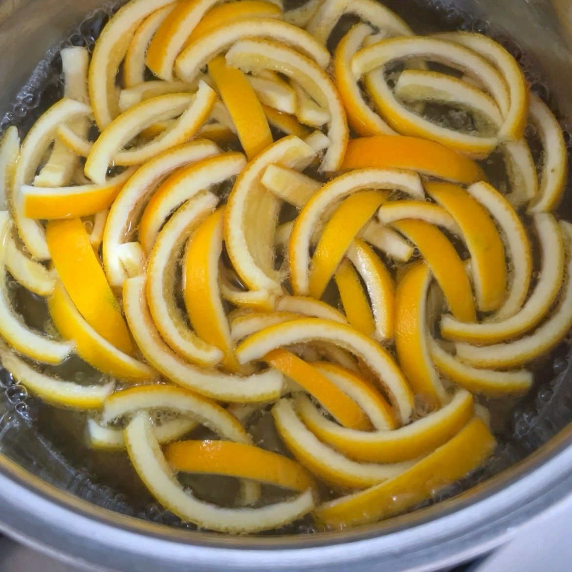 Orange peels simmer in a pot of water.