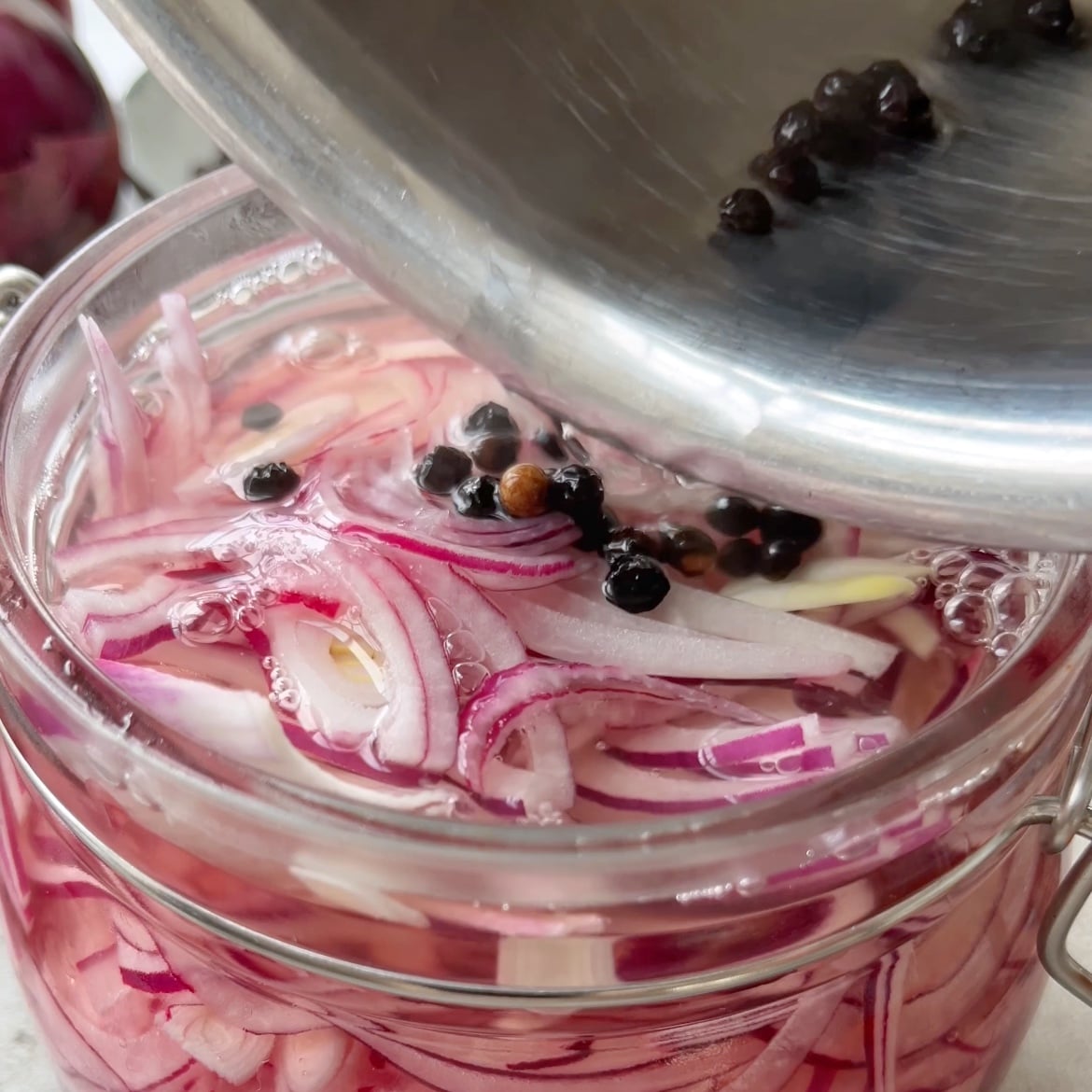 Sliced red onions are being topped with a vinegar and sugar mixture.