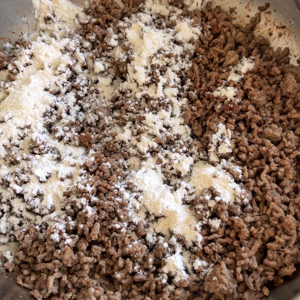 Mongolian Ground Beef cooking in a pan with white flour sprinkled on top.