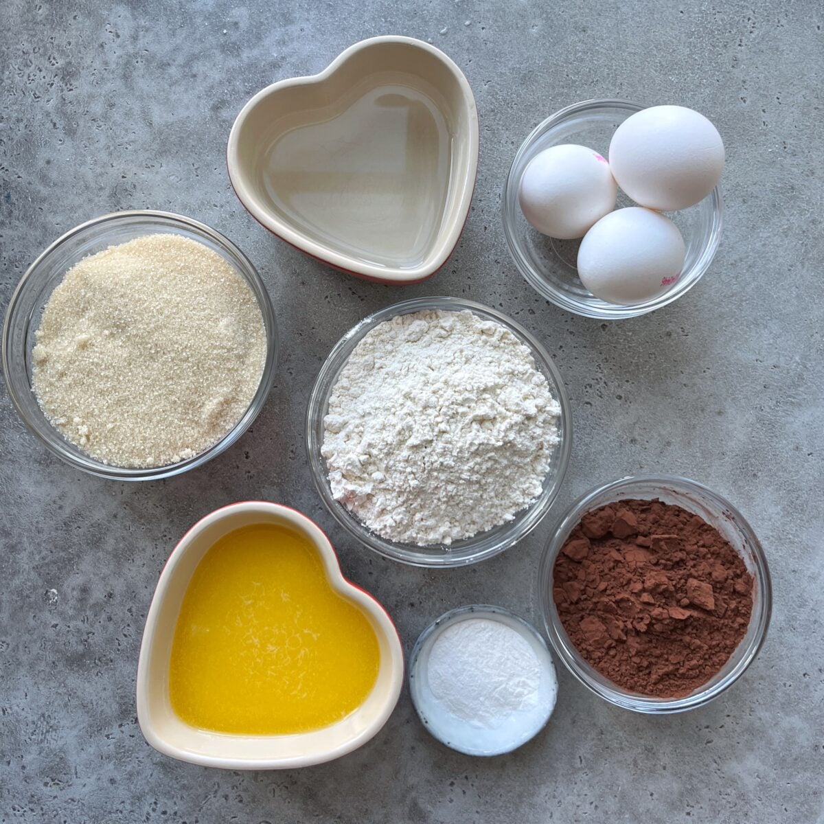 Ingredients needed for a chocolate sheet cake: eggs, flour, cane sugar, cocoa powder, baking powder, melted butter, and water.