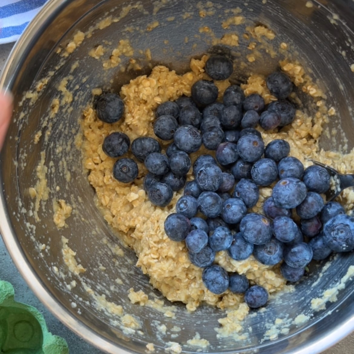 A metal mixing bowl filled with batter and fresh blueberries.