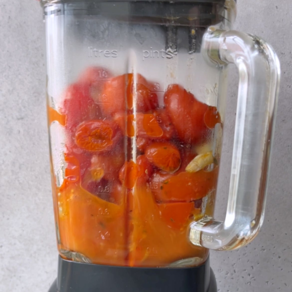 A blender filled with roasted tomatoes, garlic, and onion.