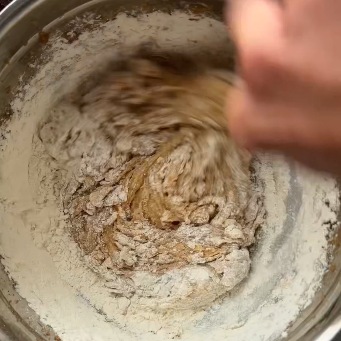 A spoon is incorporating flour into a banana bread cookie batter.