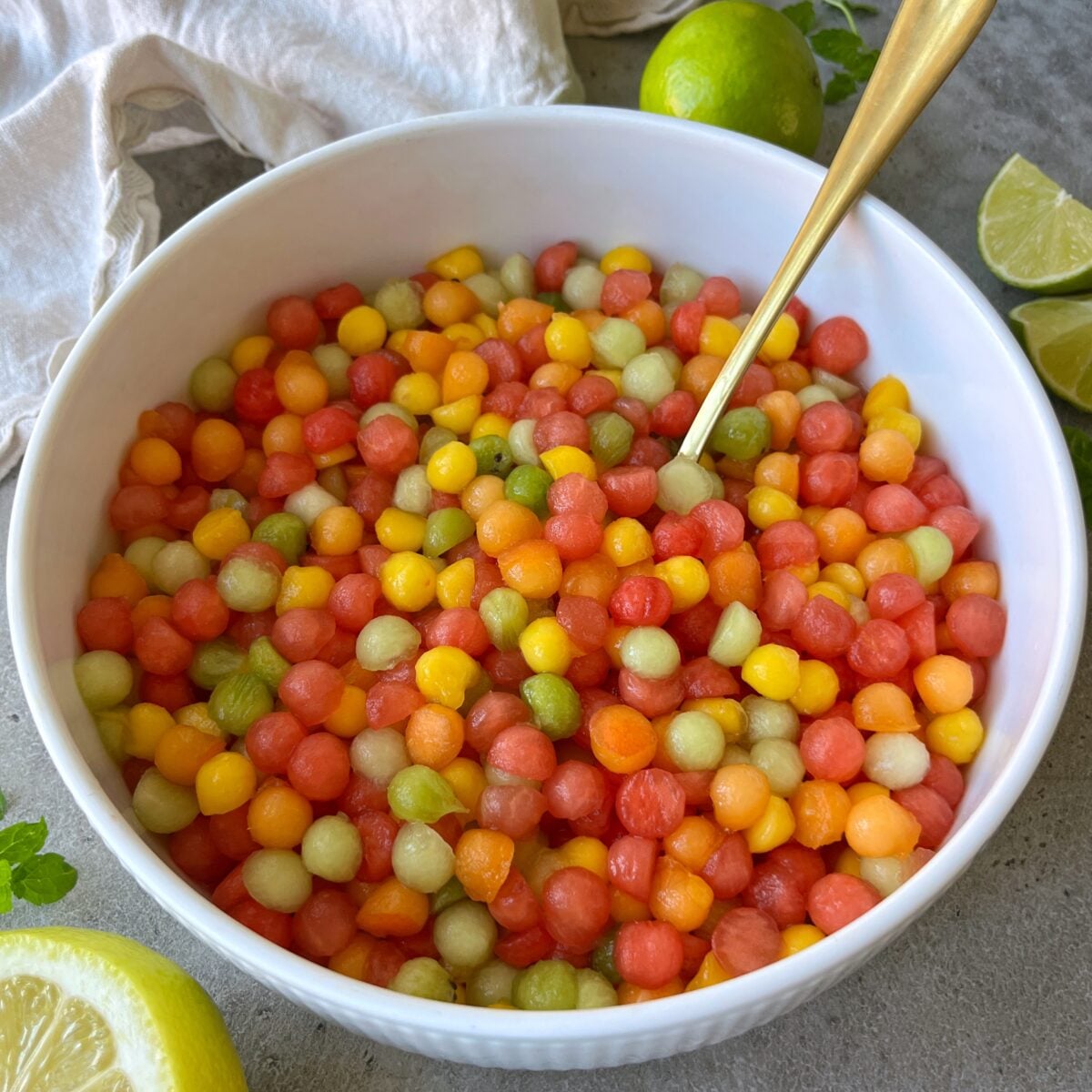 A side view of a white bowl filled with colorful fruit balls.