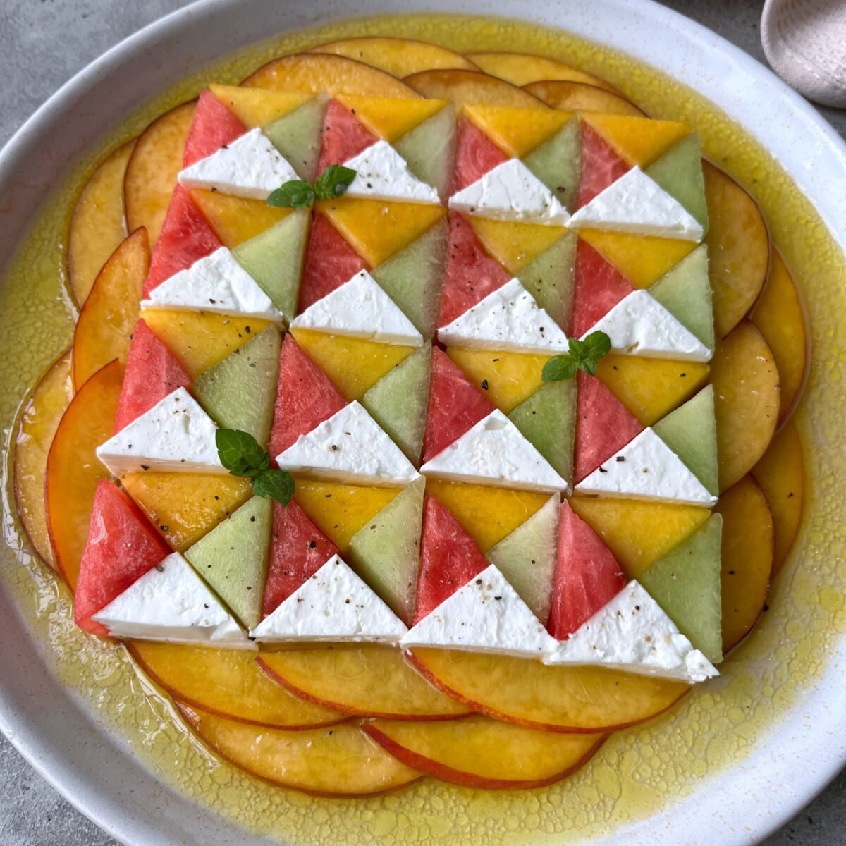 A side view of a feta cheese salad with melon arranged in a geometric pattern.