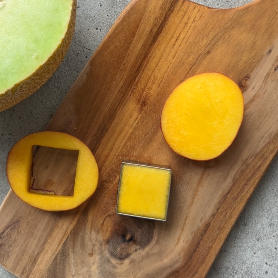 A nectarine square cut out is shown on a wooden chopping board.