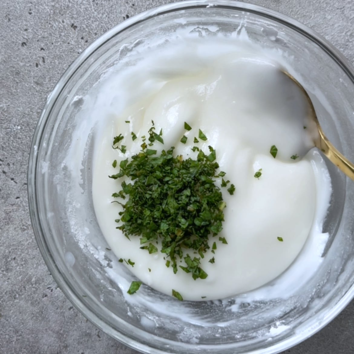 A glass bowl containing mint filling with finely chopped mint.