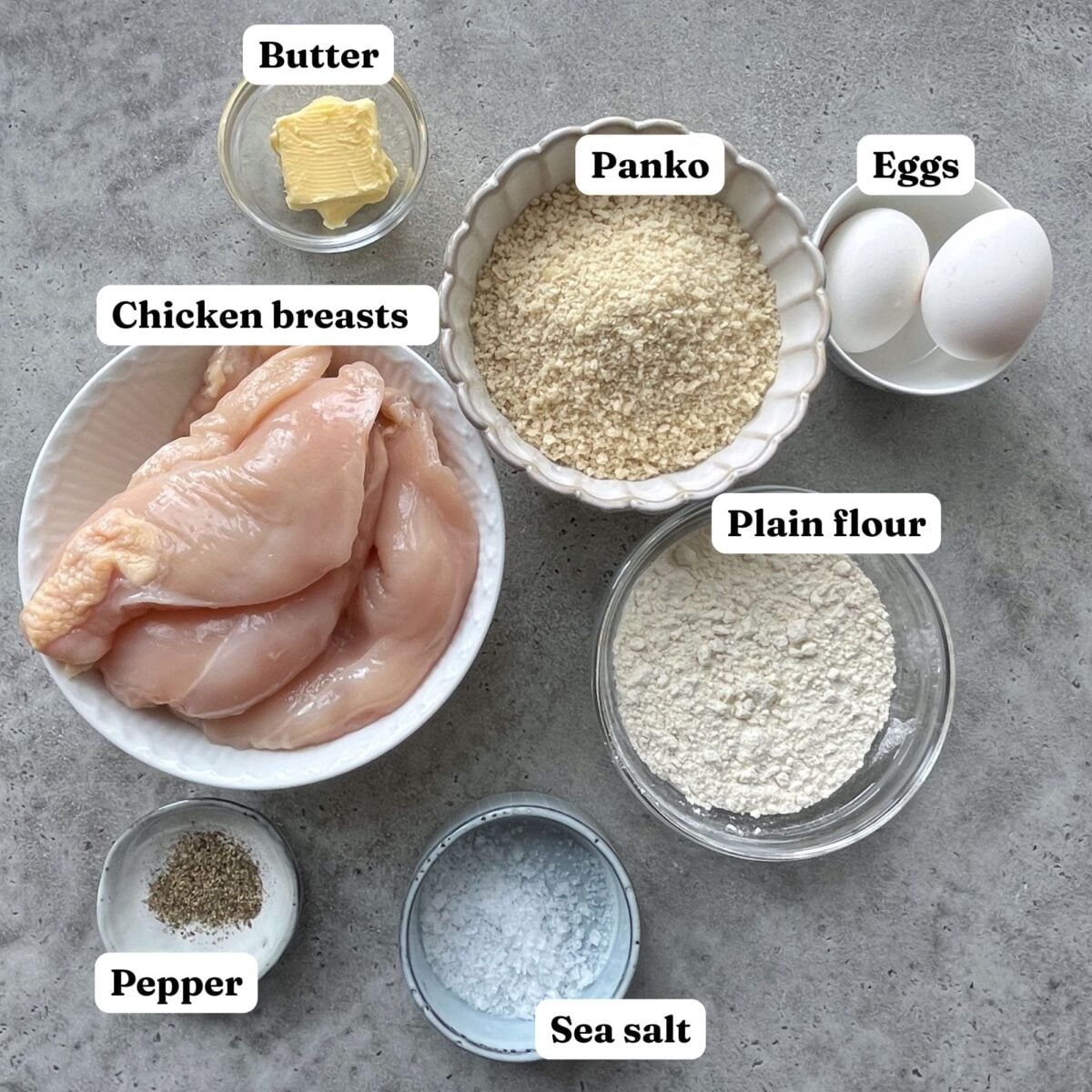 Ingredients for breaded chicken: raw chicken breasts, butter, panko, eggs, plain flour, pepper, and sea salt.
