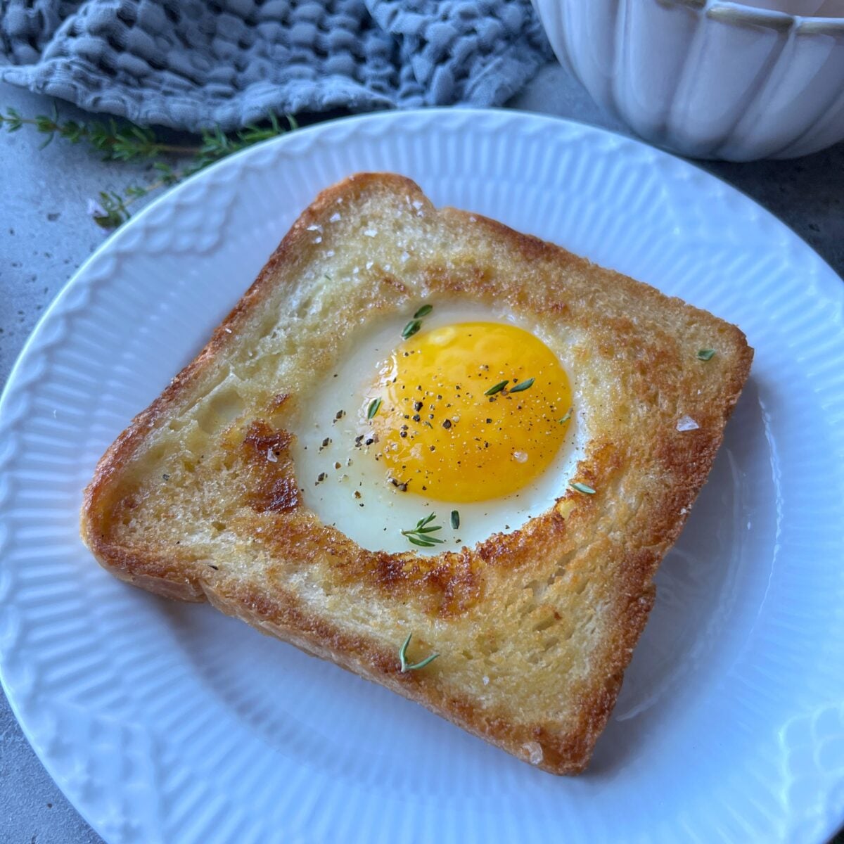 Sideview of a piece of toast with a baked egg in the center.