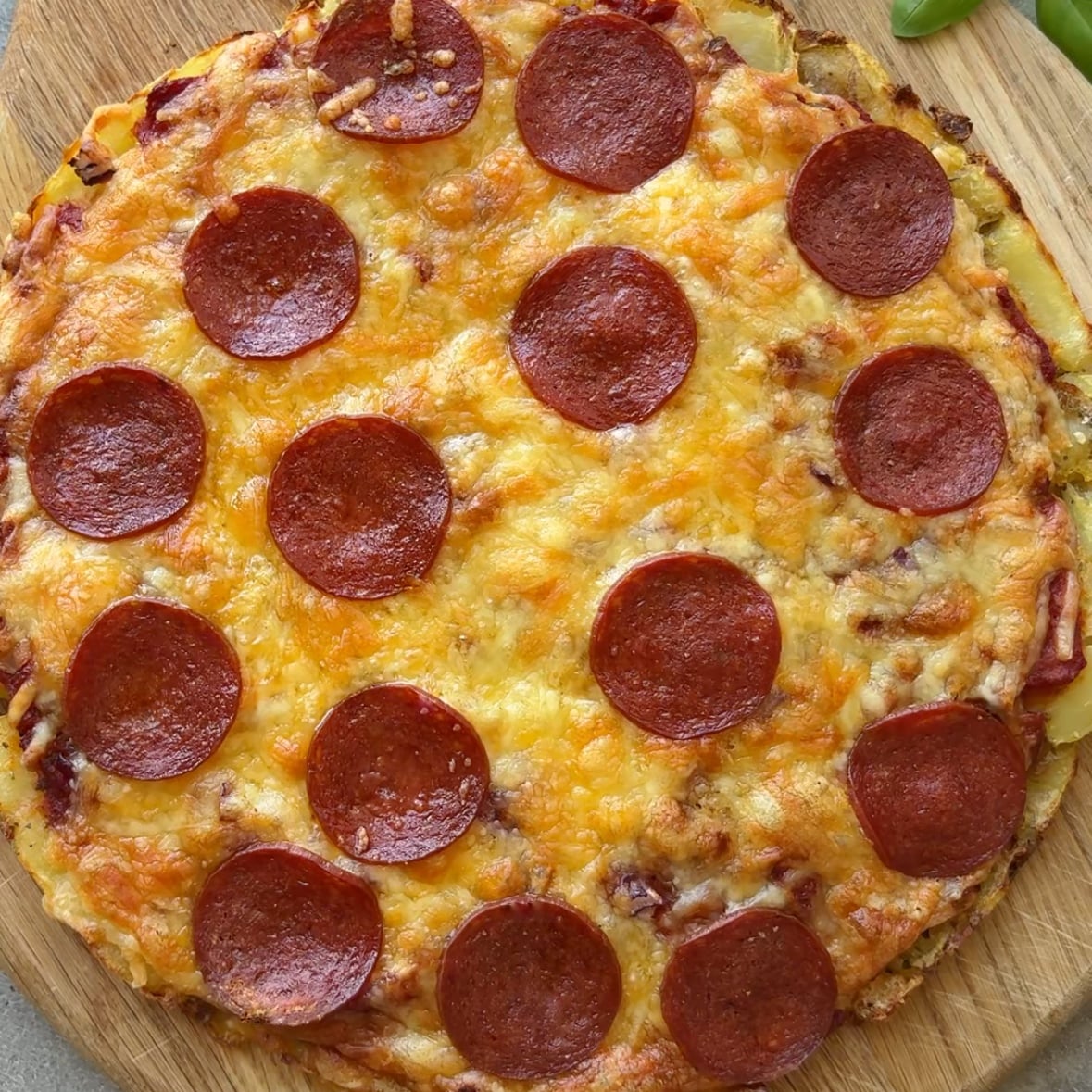 A smashed potato pizza topped with cheese and pepperoni just out of the oven.