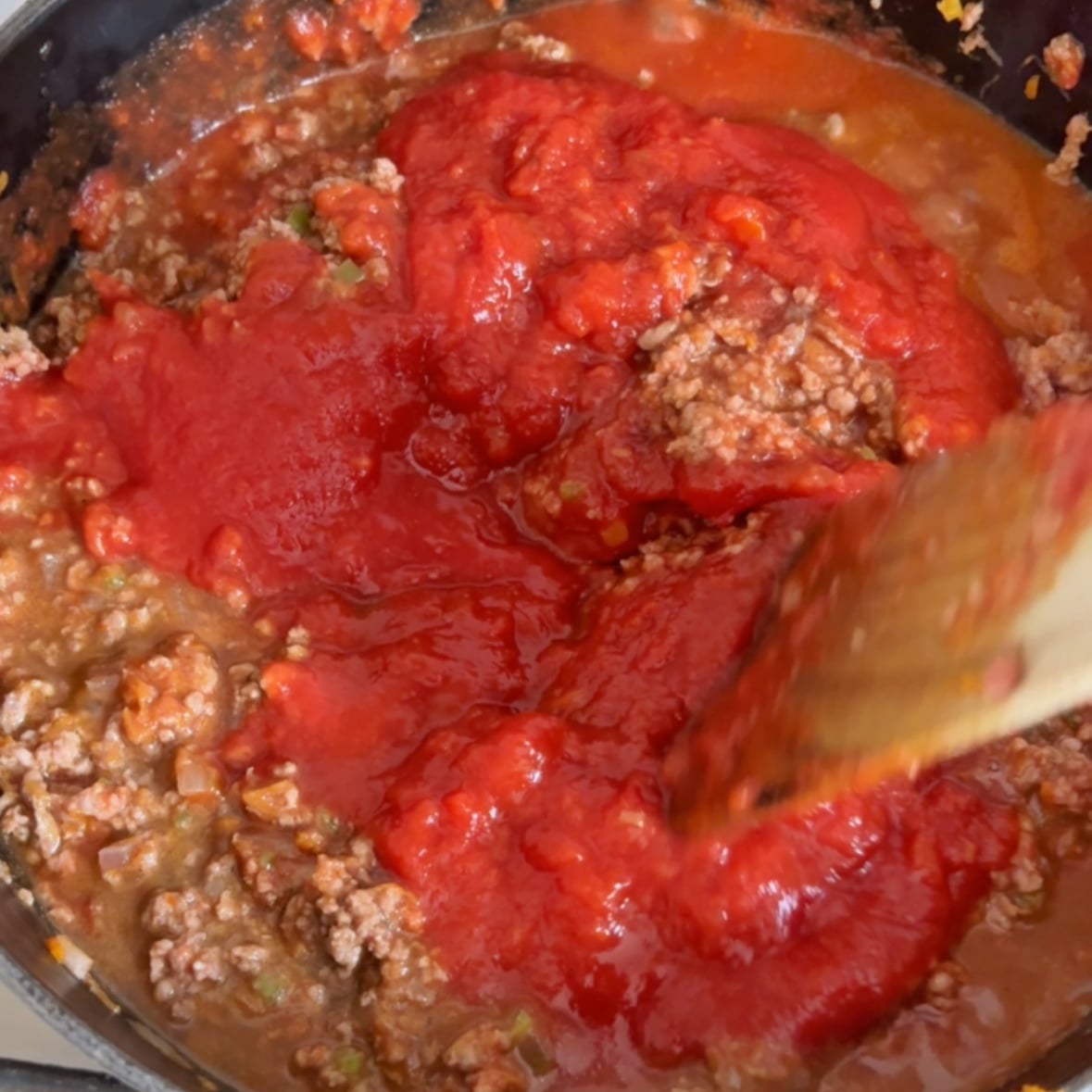 Adding tomato pasta and chopped tomatoes to the beef bolognese.