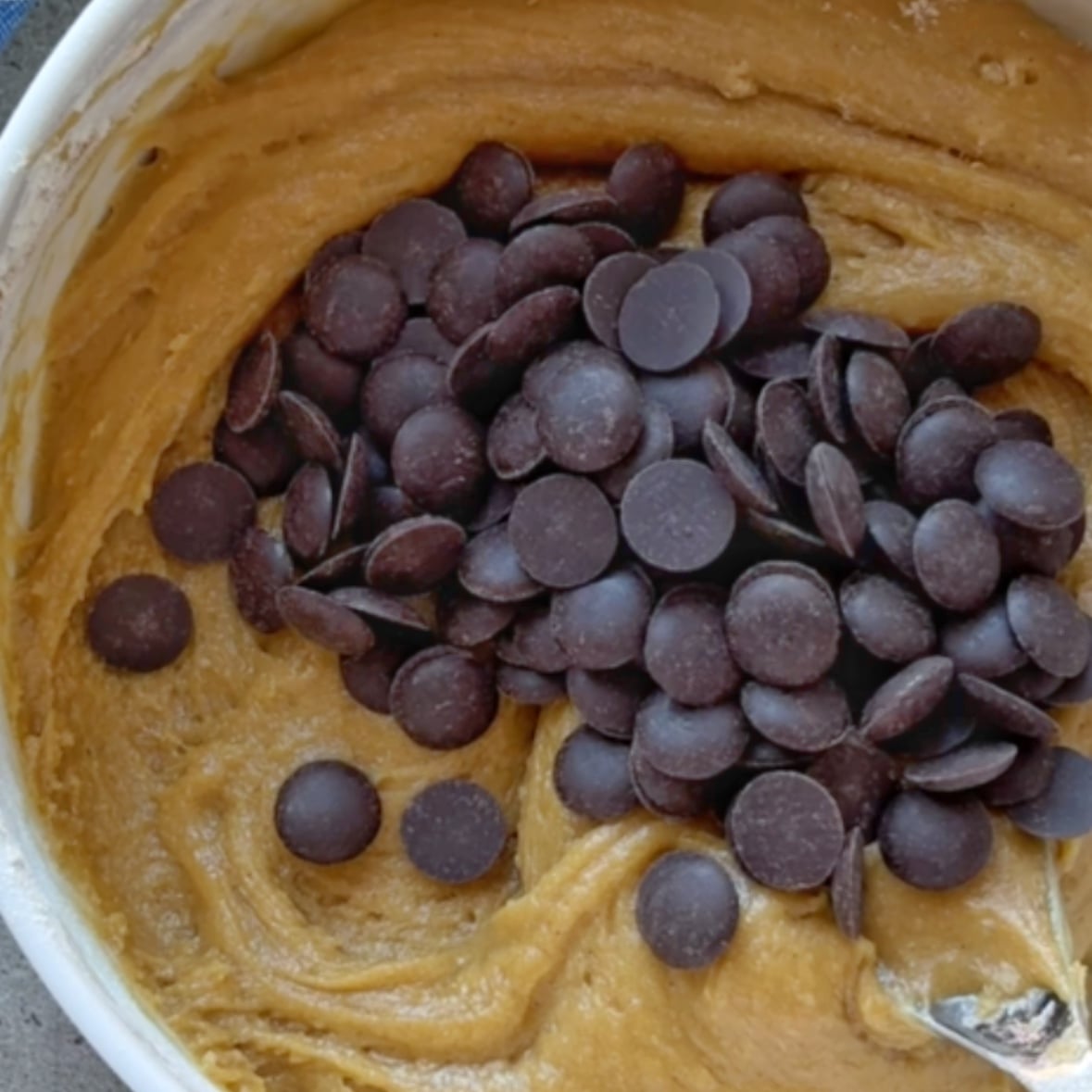 Cookie dough topped with chocolate chips, ready to be folded in.