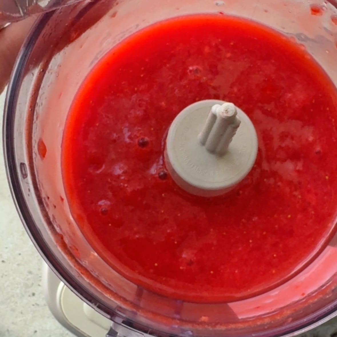 A mini food processor with pureed strawberries.