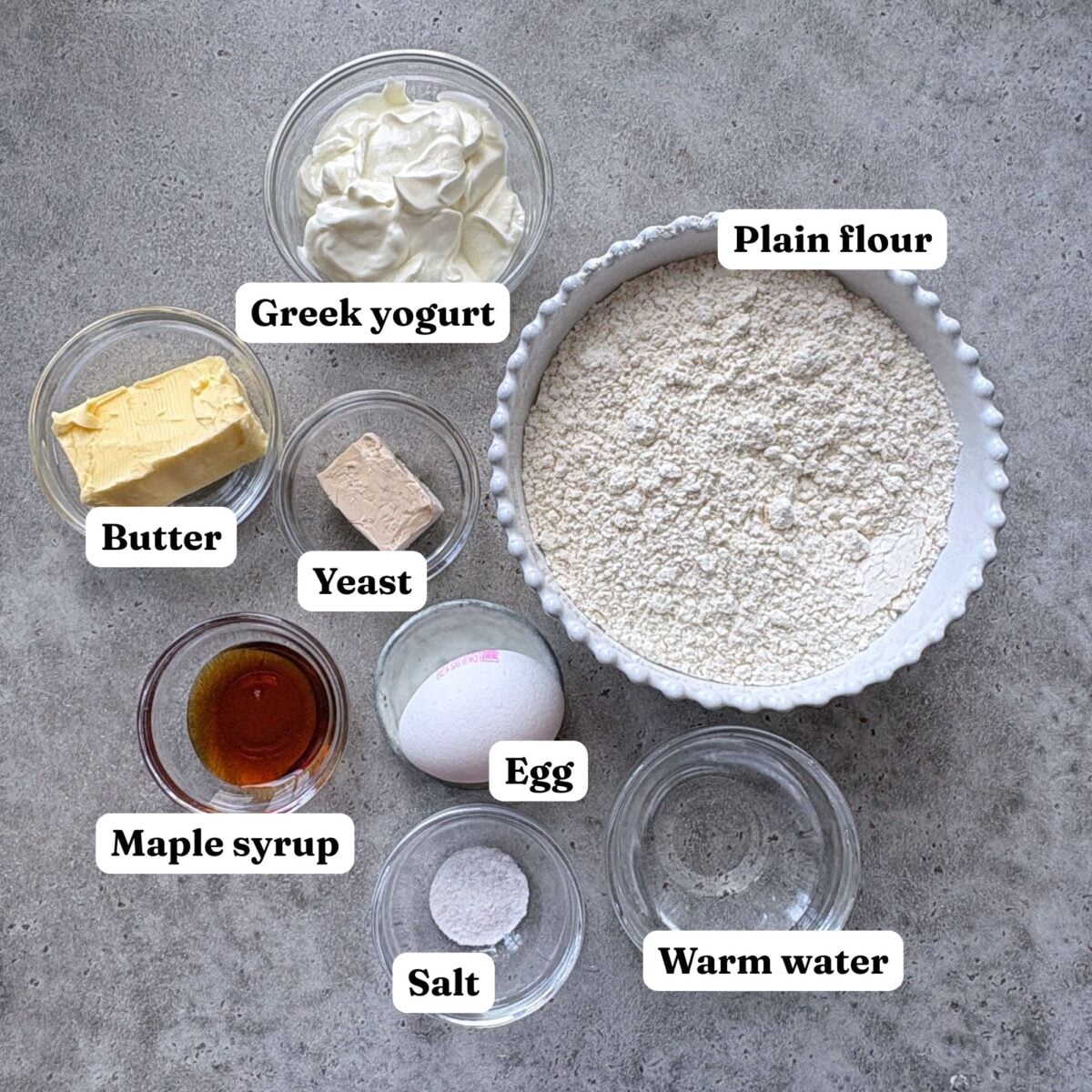 Ingredients for mini cinnamon rolls including plain flour, butter, maple syrup, yeast, baking powder, milk and one egg.